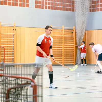 In einer Sporthalle trainieren Mitglieder des Turnvereins Landshut mit Floorballschlägern und Bällen.
