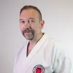 Ein Mann in Karateanzug mit dem Logo der TG Landshut steht vor neutralem Hintergrund.