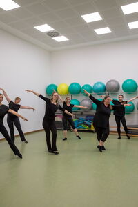 Eine Gruppe von Frauen führt Fitness-Tanzübungen in einem Turnraum des Vereins TGL Landshut aus.