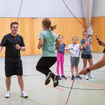 In der Turnhalle der Turngemeinde Landshut springt ein Mädchen Seil, während andere Kinder zuschauen.
