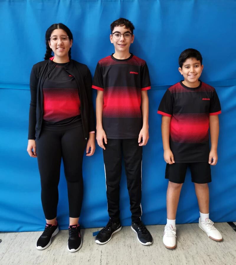 Eine Gruppe junger Tischtennisspieler der Turngemeinde Landshut posiert mit Schlägern in einer Sporthalle.