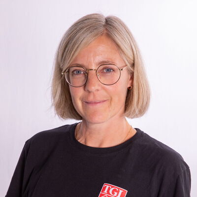Eine Frau mit Brille trägt ein schwarzes T-Shirt mit dem Logo von TGL, einem Sportverein aus Landshut.