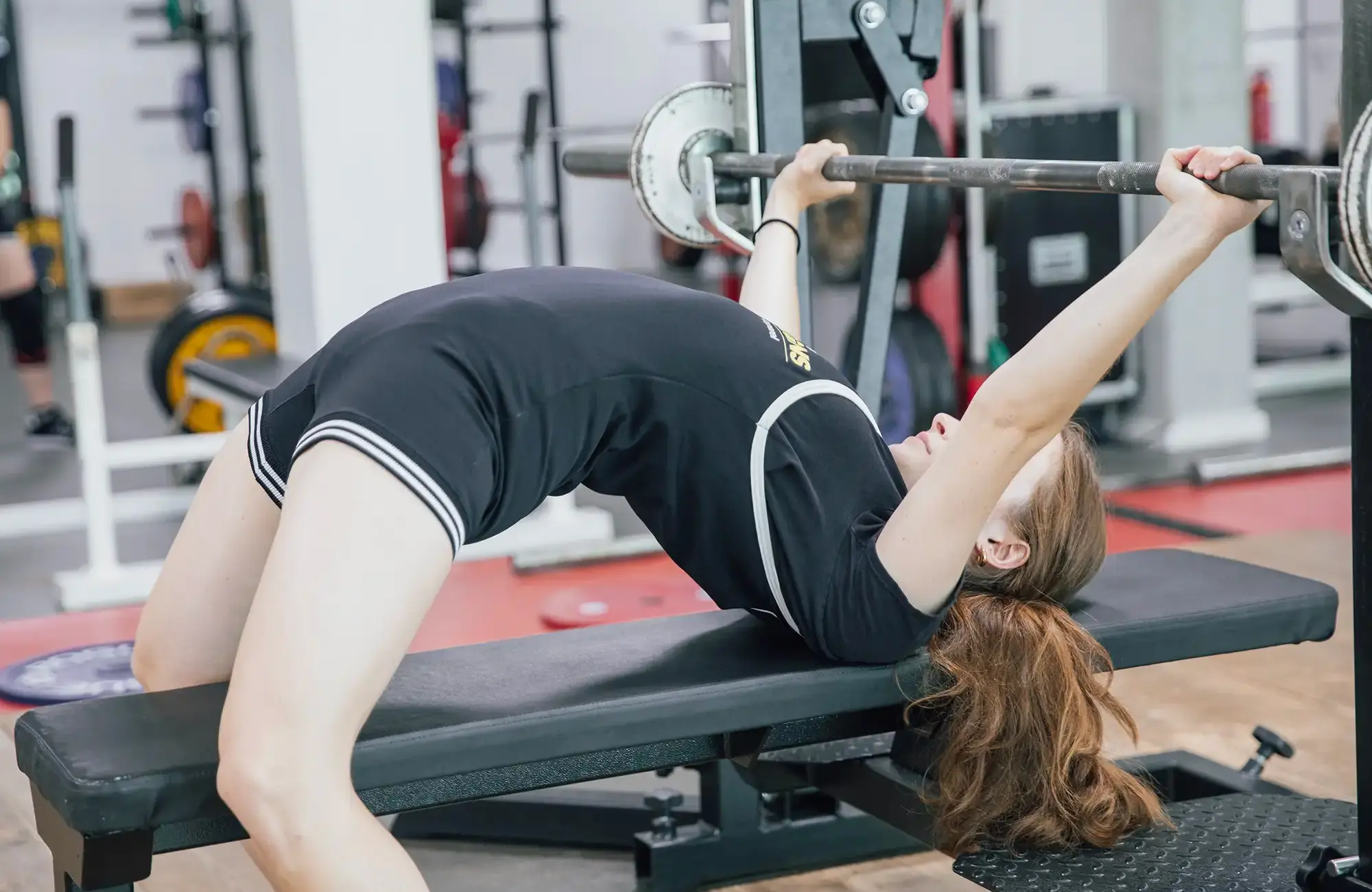 Eine Frau hebt im Fitnessstudio eine Hantel auf der Bank, ein typisches Training im Turngemeinde Landshut Sportverein.