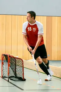 Ein Spieler der Turngemeinde Landshut dribbelt mit einem Floorball-Schläger in einer Sporthalle am Tor vorbei.