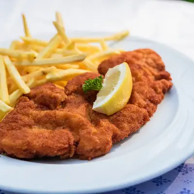 Ein knuspriges Schnitzel mit Pommes und einer Zitronenscheibe auf einem Teller, ideal für ein Turngemeinde-Treffen.