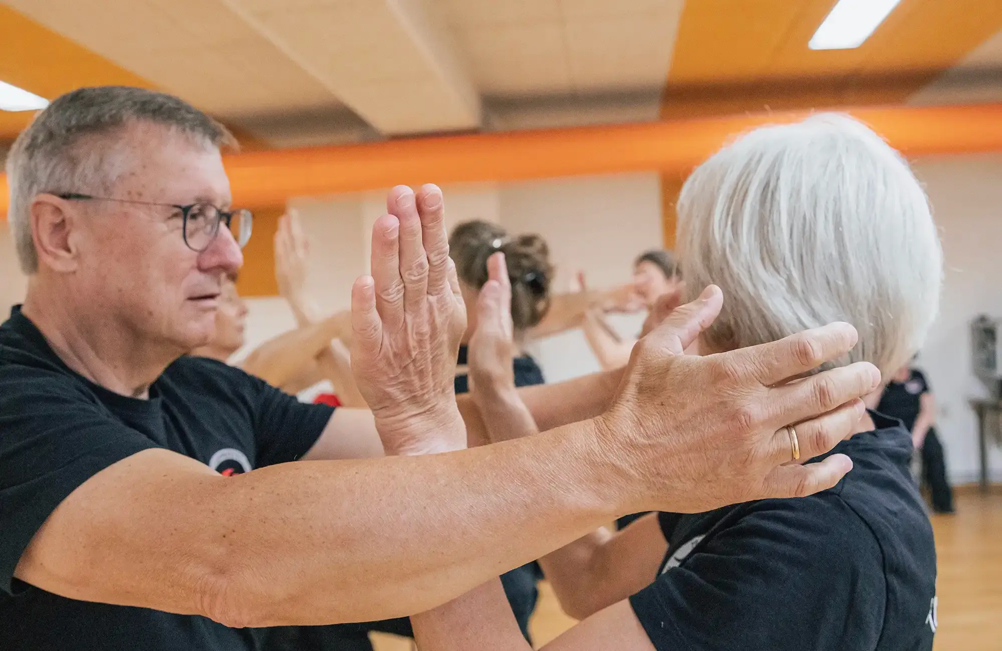 Eine Gruppe von Senioren übt konzentriert Kampfsporttechniken im Turngemeinde-Verein in Landshut.