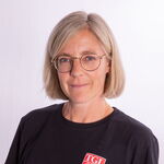 Eine Frau mit Brille trägt ein schwarzes T-Shirt mit dem Logo von TGL, einem Sportverein aus Landshut.