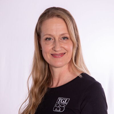 Eine Frau in einem TGL-Shirt lächelt freundlich, repräsentiert den Sportverein Turngemeinde Landshut.