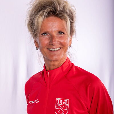 Eine lächelnde Frau trägt eine rote TGL-Jacke, symbolisierend den Sportgeist des Vereins Turngemeinde Landshut.