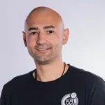 Ein lächelnder Mann trägt ein schwarzes T-Shirt mit dem Logo der Turngemeinde Landshut.