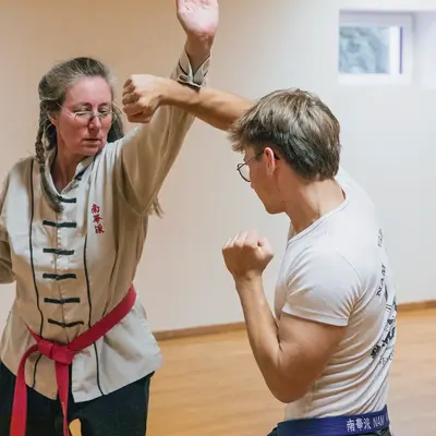 Zwei Personen üben Kampfsporttechniken in einem hellen Raum, als Teil des Landshut Vereins Turngemeinde.
