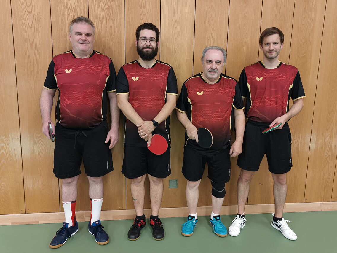 Vier Tischtennisspieler der Herren II der Turngemeinde Landshut posieren in Sportkleidung vor einer Holzwand.