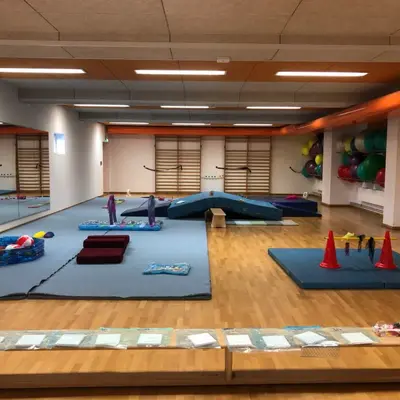 Eine helle Turnhalle in Landshut ist für Babykurse der Turngemeinde mit buntem Spielzeug und Matten ausgestattet.