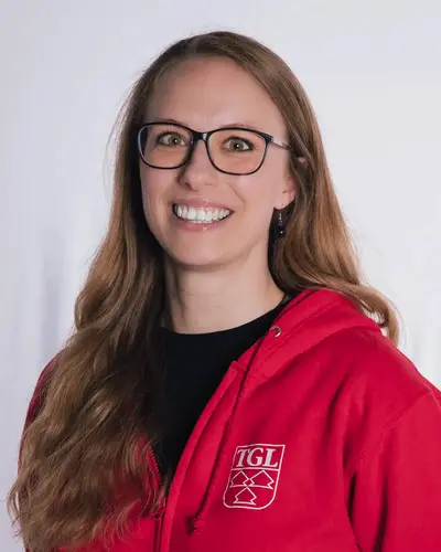 Eine lächelnde Frau in rotem Hoodie mit TGL-Logo repräsentiert den Sportverein Turngemeinde Landshut.