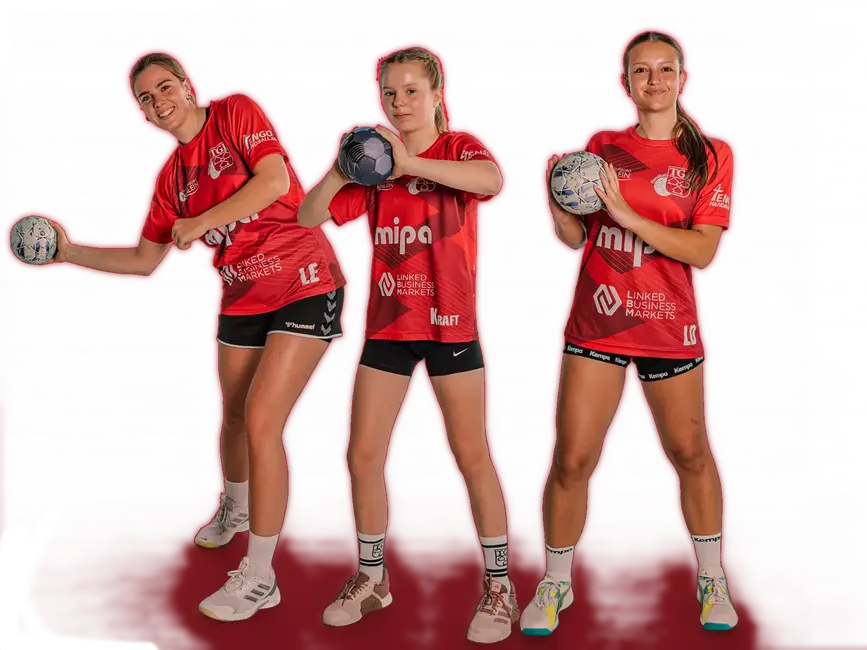 Eine fröhliche Handballmannschaft der Turngemeinde Landshut posiert in roten Trikots mit Bällen.