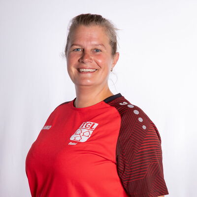 Eine Frau im TGL-Trikot lächelt vor einem neutralen Hintergrund, repräsentiert die Turngemeinde Landshut im Sport.