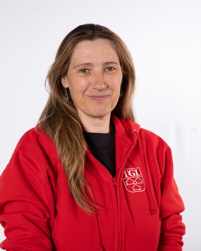Eine Frau in einer roten TGL-Jacke lächelt freundlich, repräsentiert den Sportverein Turngemeinde Landshut.