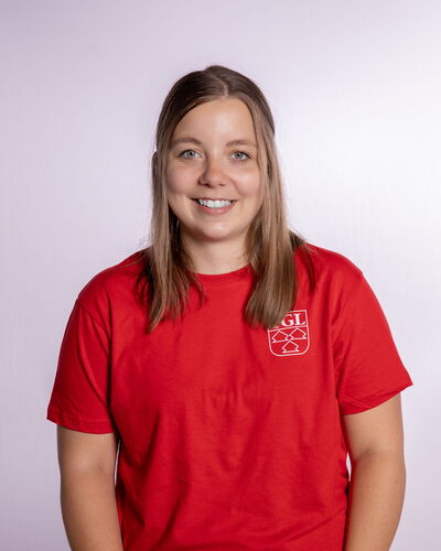 Eine lächelnde Frau in einem roten T-Shirt mit TGL-Logo repräsentiert den Sportverein Turngemeinde Landshut.