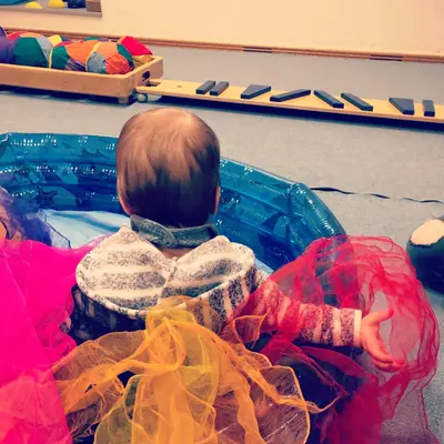 Ein Baby sitzt in einem bunten Pool voller Tücher bei einem Sportkurs der Turngemeinde Landshut.