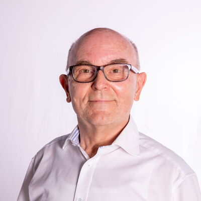 Ein Mann mit Brille und weißem Hemd, möglicherweise Mitglied der Turngemeinde Landshut, lächelt freundlich in die Kamera.