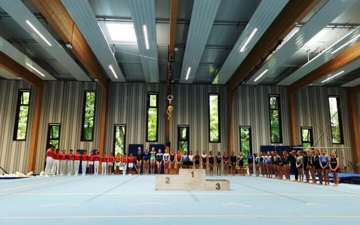 Athleten der Turngemeinde Landshut stehen bei der Vereinsmeisterschaft aufgereiht vor dem Siegerpodest in der Sporthalle.