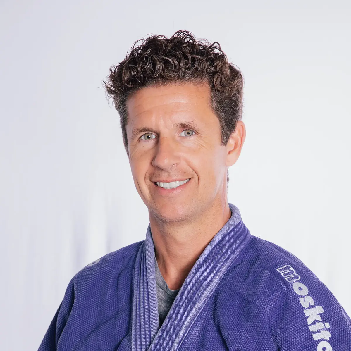 Ein Mann in einem blauen Judoanzug lächelt freundlich in die Kamera, repräsentiert den Sportverein Landshut.