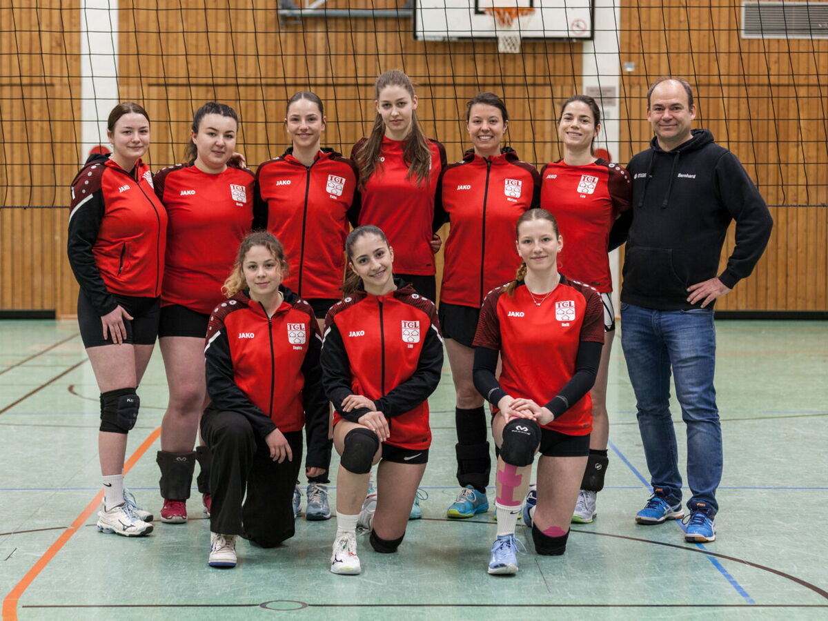 Das Damen Team in einheitlichen Sporttrikot posieren in einer Sporthalle der Turngemeinde Landshut für ein Teamfoto.