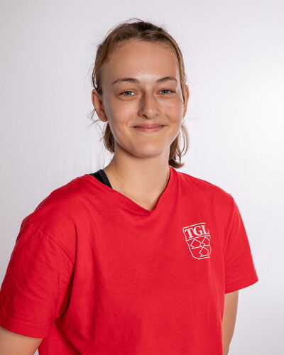 Eine junge Frau im roten TGL-Shirt lächelt freundlich in die Kamera, repräsentativ für den Verein in Landshut.