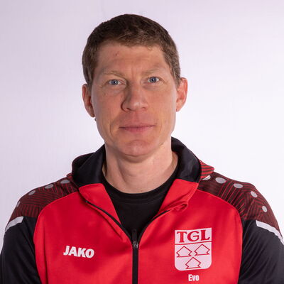 Ein Mann in einer roten Jacke mit TGL-Logo vertritt den Sportverein Turngemeinde Landshut.