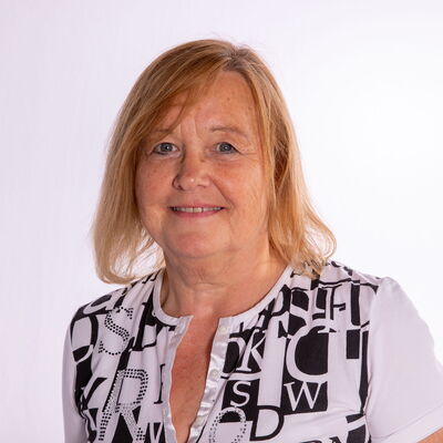 Eine Frau mit kurzem, blondem Haar trägt ein gemustertes Shirt, ideal für den Tanzsport im Turngemeinde Landshut Verein.