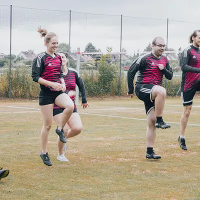 Eine Gruppe von Sportlern der Turngemeinde Landshut trainiert synchron auf einem Sportfeld.