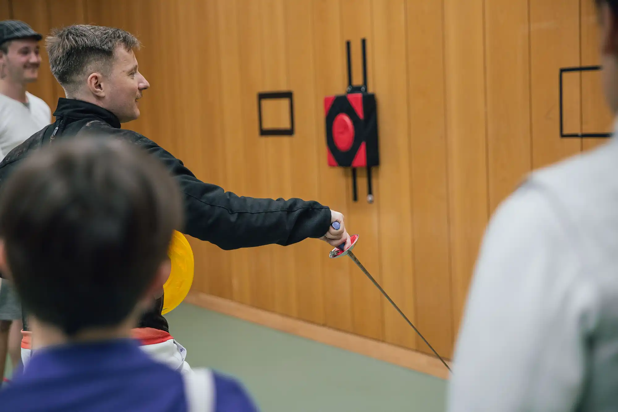 Ein Mann demonstriert Fechttechniken vor einer Gruppe im Sportverein Turngemeinde Landshut.