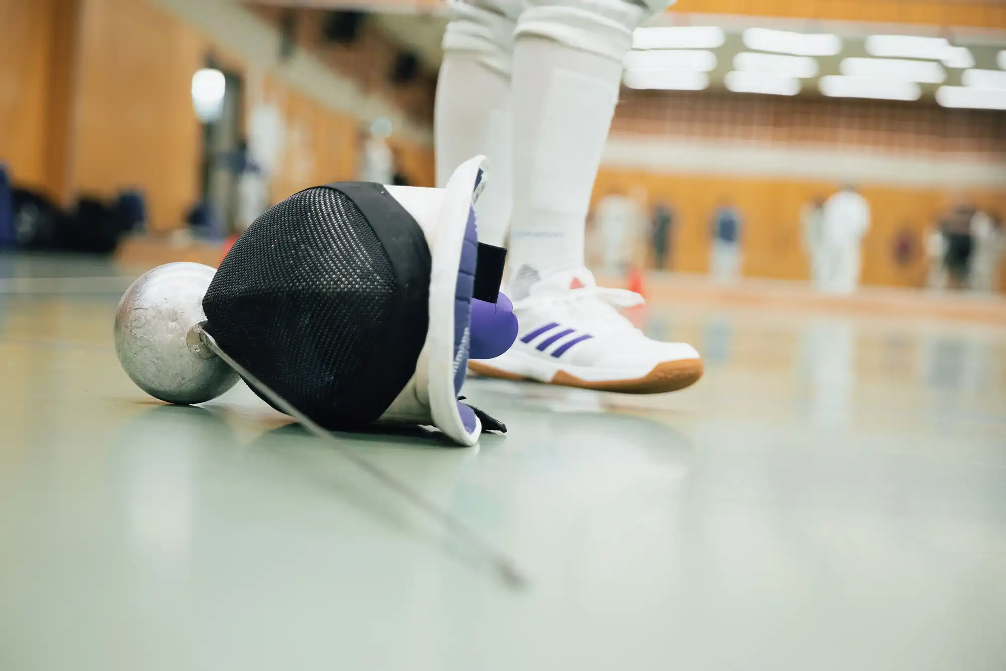 Ein Fechthelm und ein Degen liegen auf dem Boden einer Sporthalle des Vereins Turngemeinde Landshut.