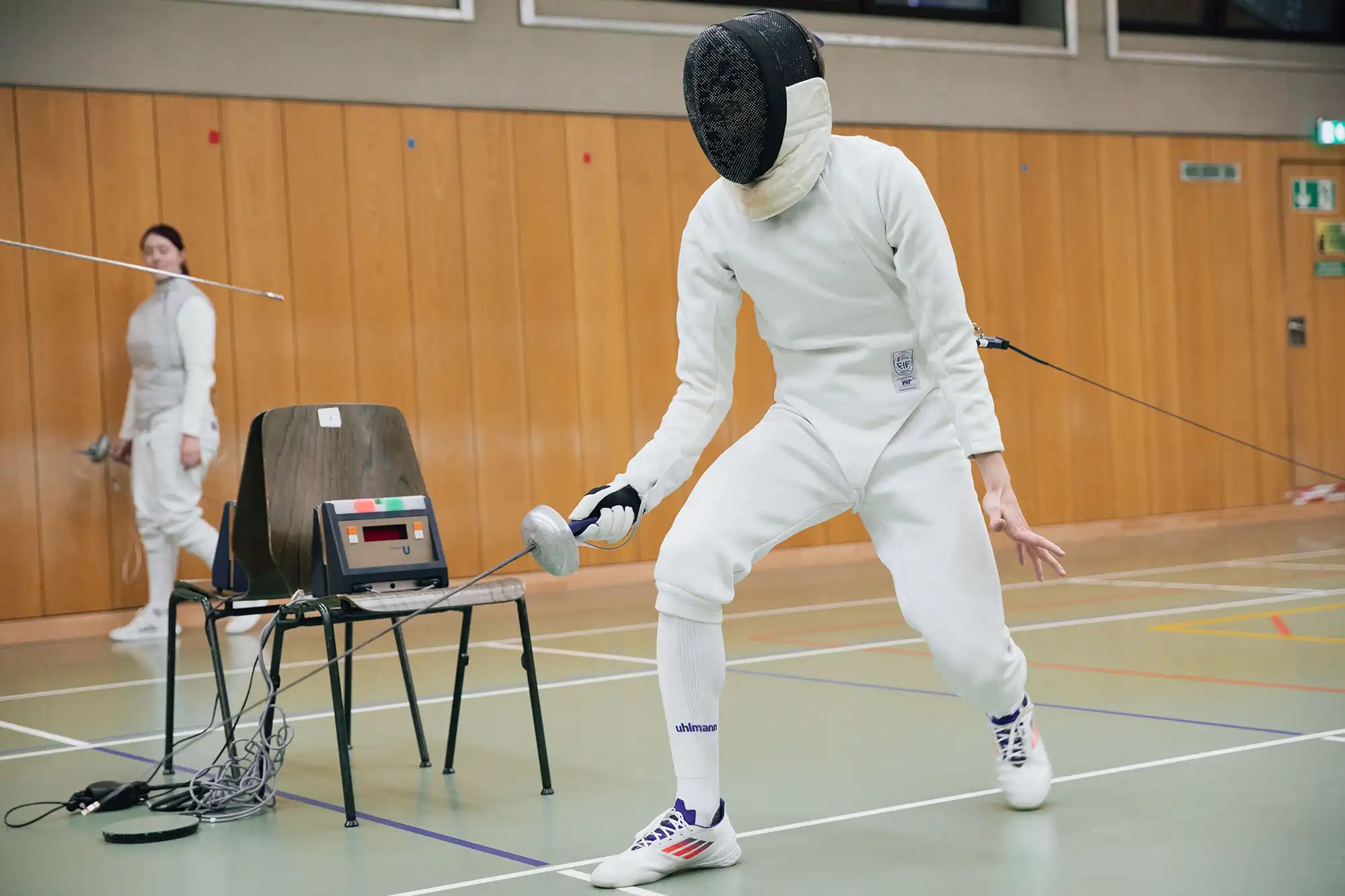 Ein Fechter im weißen Anzug konzentriert sich während eines Turniers im Sportverein Landshut auf seinen nächsten Angriff.
