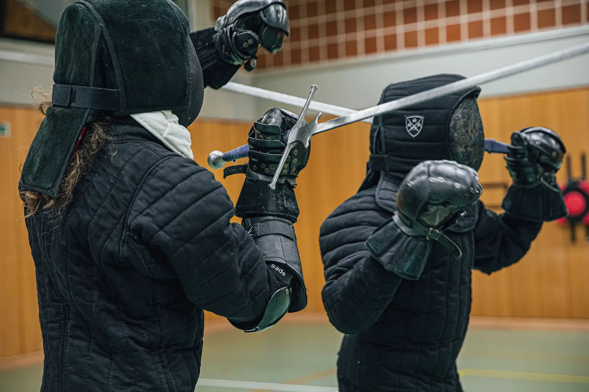 Zwei Fechter in voller Schutzkleidung kreuzen ihre Schwerter während eines Turngemeinde-Trainings in Landshut.