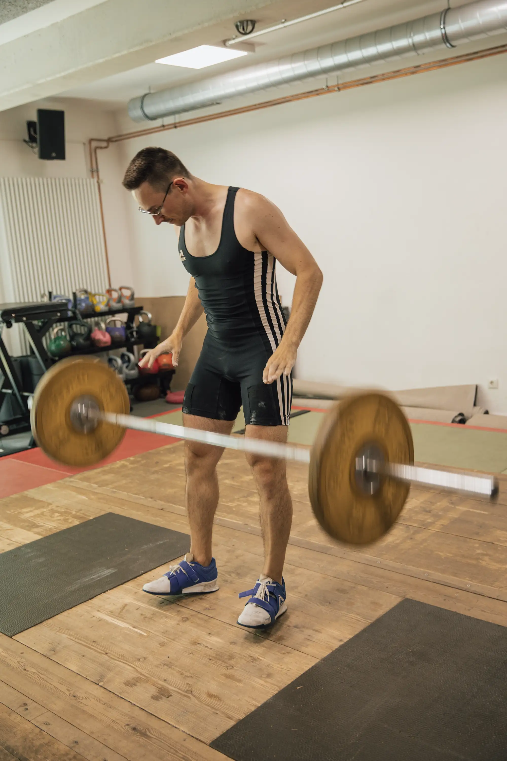 Ein Mann in Sportkleidung hebt eine Langhantel in einem Trainingsraum der Turngemeinde Landshut.