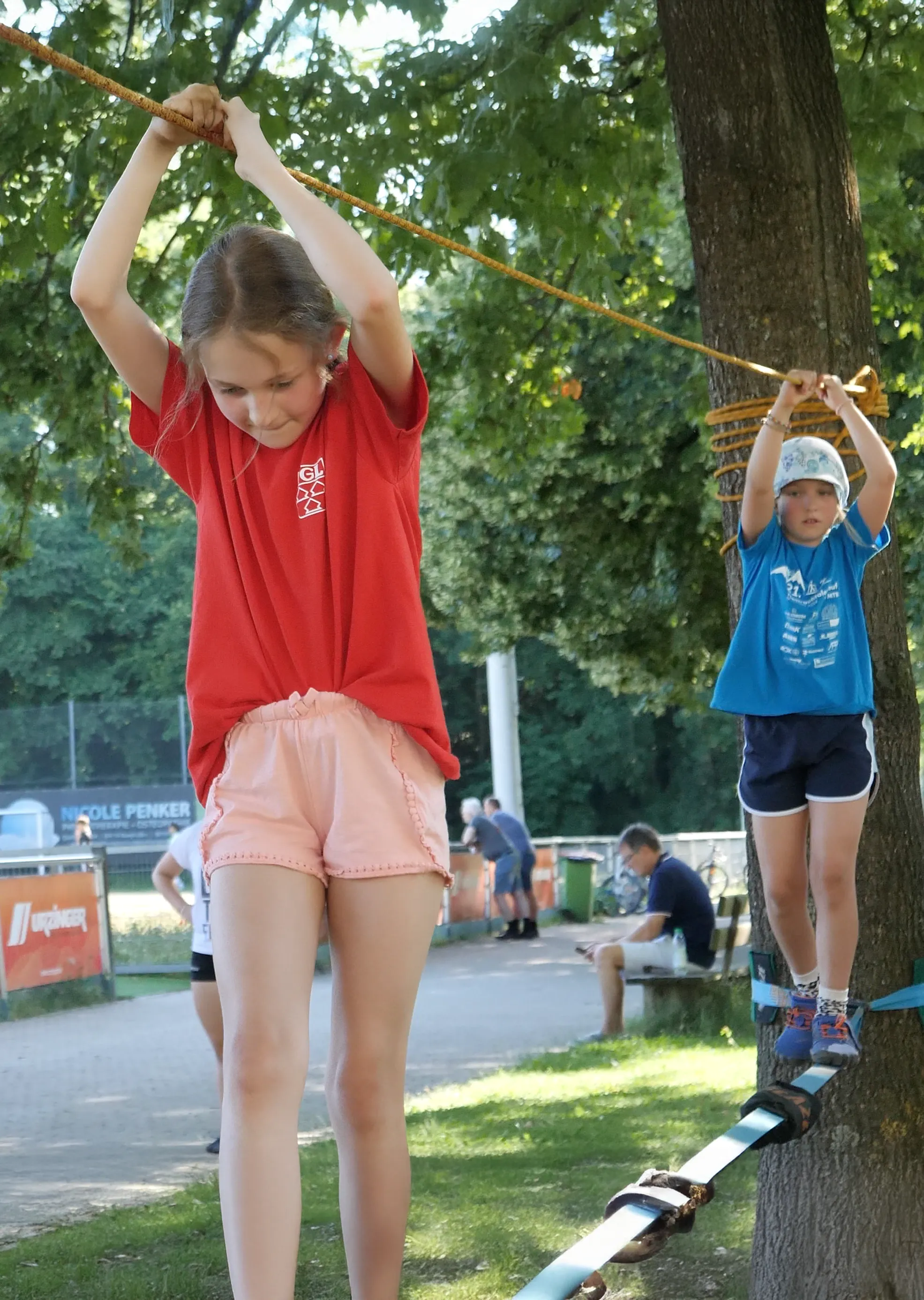 Zwei Kinder balancieren konzentriert auf einem Slackline-Seil bei einem Sportevent der Turngemeinde Landshut.
