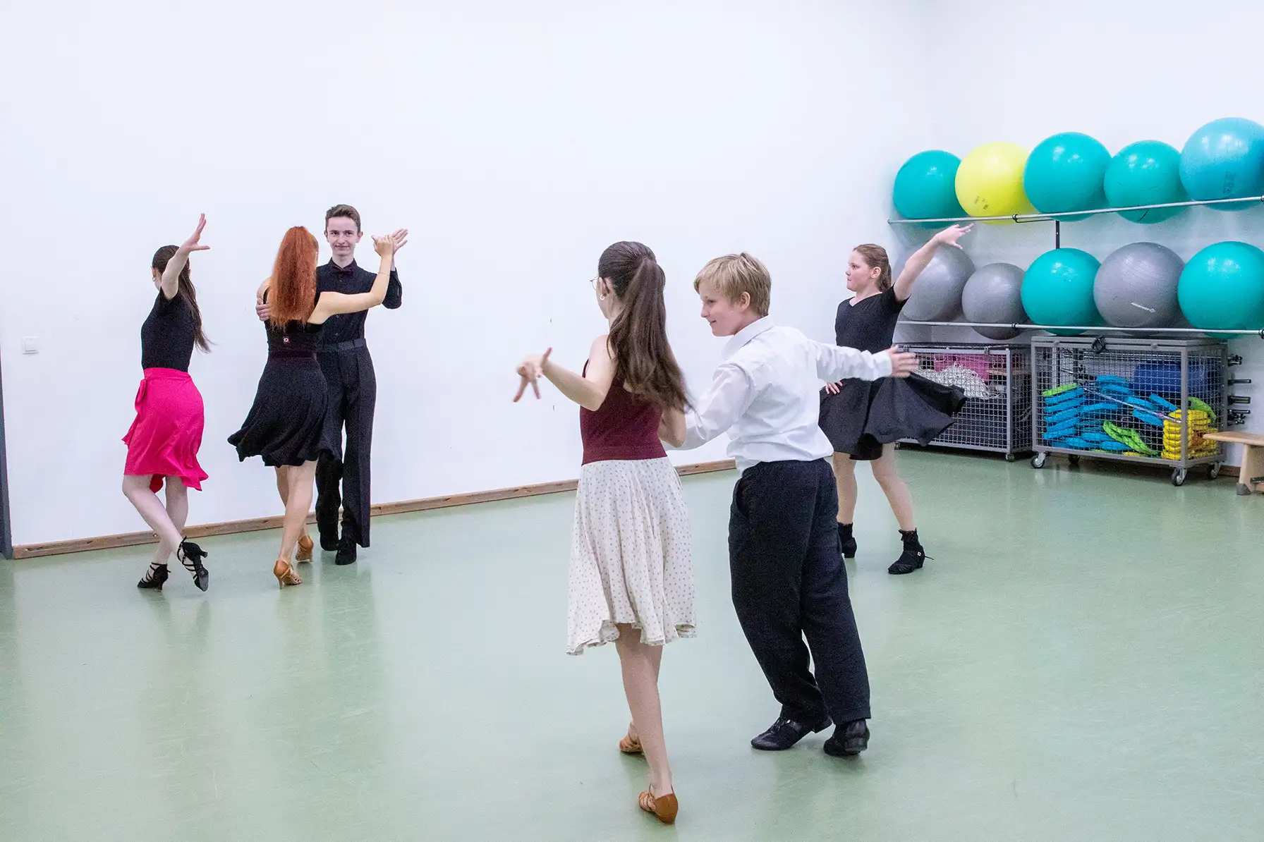 Mehrere Paare tanzen schwungvoll in einem Übungsraum der Turngemeinde Landshut, umgeben von Fitnessbällen.